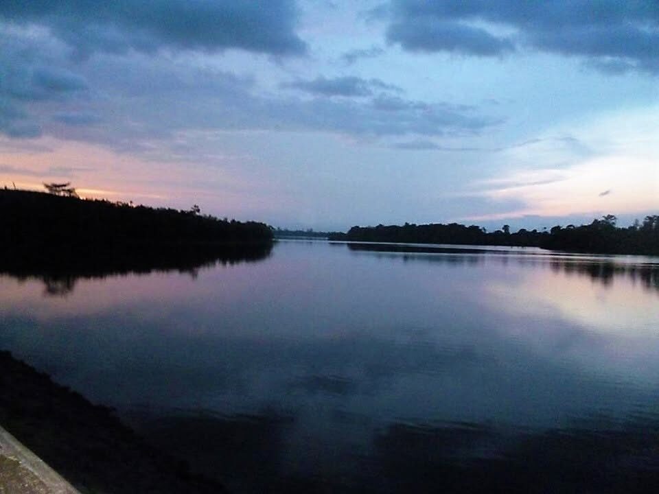 Le lac Zizebo de Kibouo au crépuscule, eaux calmes et rive boisée près de Daloa.