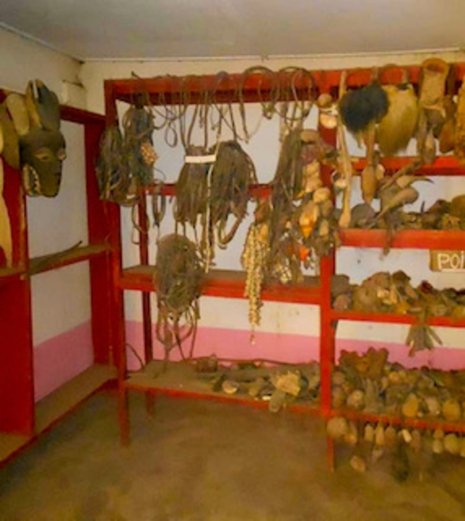 Masques et objets rituels accrochés aux étagères du musée.