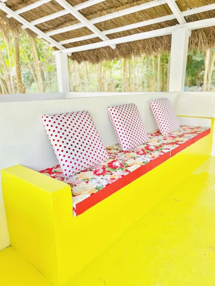 Banquette jaune aux coussins fleuris au domaine Pacifik Lodges de Kibouo.